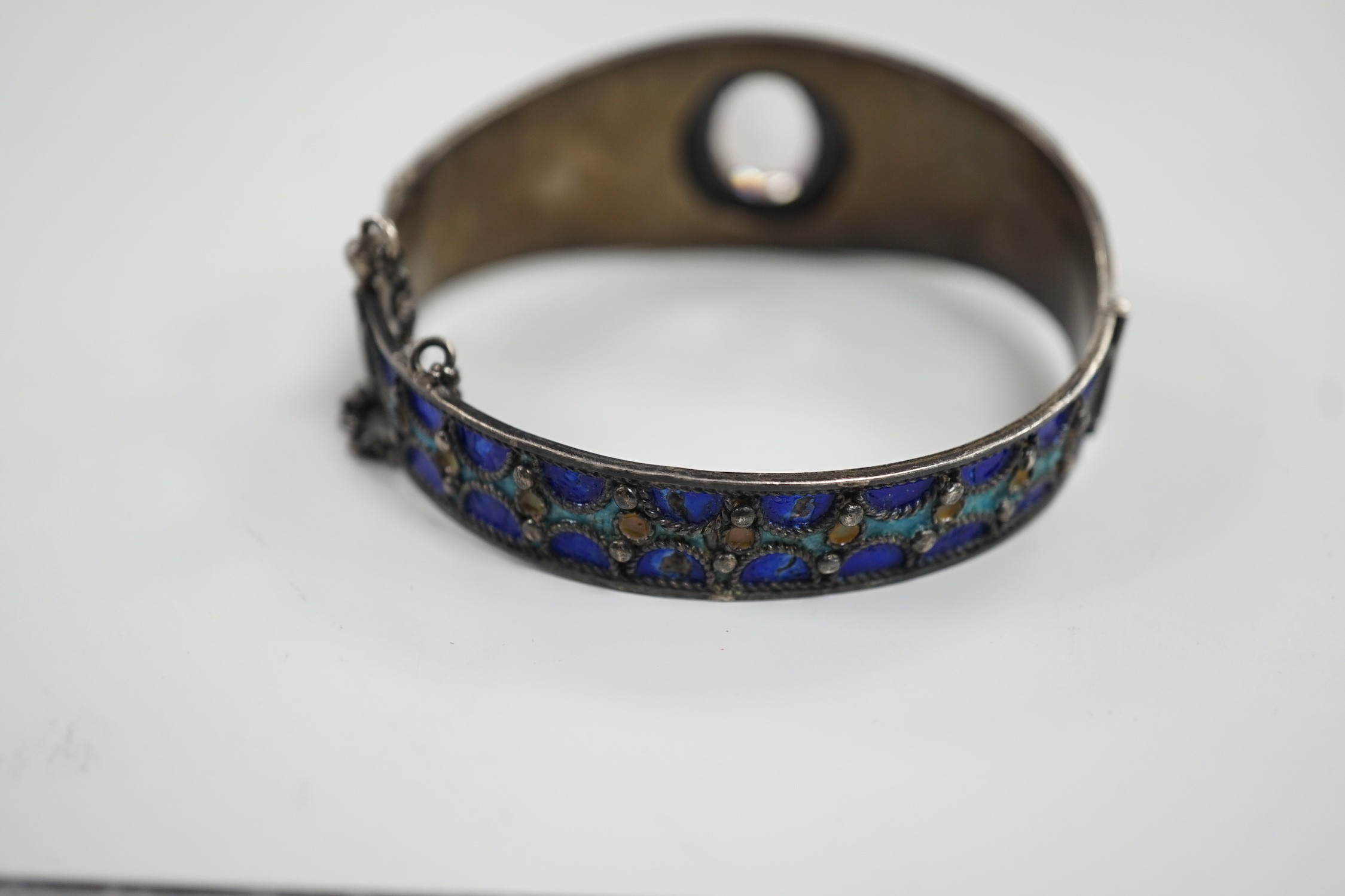 An early to mid 20th century continental white metal polychrome enamel and foil backed oval cut rock crystal set hinged bangle, interior diameter approximately 62mm.